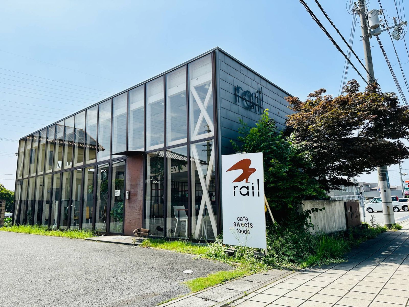閉店前の cafe rail 飾磨の店。全面ガラス張りの建物の前に、鳥のマークと rail の白い看板が立っている